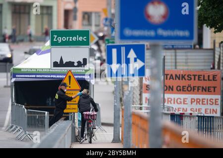 09. Juni 2020, Sachsen, Görlitz: Ein polnischer Grenzpolizist steht auf der Brücke der Freundschaft an der polnischen Grenze vor Zgorzelec und überprüft mit einem Thermometer die Körpertemperatur einer Radfahrerin, die auf die polnische Seite fahren will. Foto: Sebastian Kahnert/dpa-Zentralbild/dpa Stockfoto