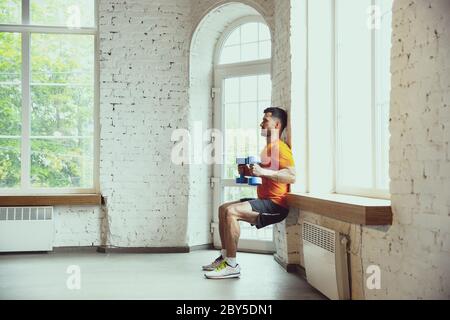 Sit ups. Junge kaukasischen Mann Training zu Hause während der Quarantäne des Coronavirus Ausbruch, tun Übungen der Fitness, Aerobic. Sportivfähigkeit während der Isolierung. Wellness, Sport, Bewegungskonzept. Stockfoto