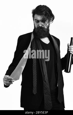 Bärtiger Mann, langer Bart. Brutaler kaukasischer Hipster mit Schnurrbart in schwarzem Anzug mit bunten Krawatten auf den Schultern, die Flasche auf weißem Studiohintergrund isoliert halten Stockfoto