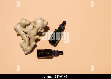 Bio Ingwer ätherisches Öl in dunkler Glasflasche und Ingwerwurzel, Kopierraum. Stockfoto