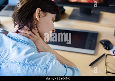 Porträt von müde Grafikdesigner arbeiten Überstunden im Büro. Gestresste Arbeiter haben Augenstrapazheitssymptome. Retoucher Arbeitsplatz im Fotostudio. Burnout Stockfoto