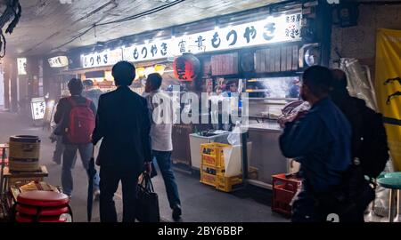 Leute, die in der Hintergasse des Yurakucho-Bezirks, Tokio, Japan bei Nacht spazieren gehen. Stockfoto