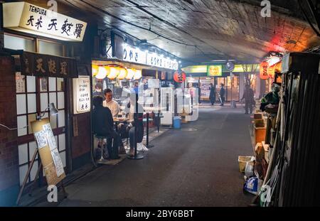 Leute, die in der Hintergasse des Yurakucho-Bezirks, Tokio, Japan bei Nacht spazieren gehen. Stockfoto