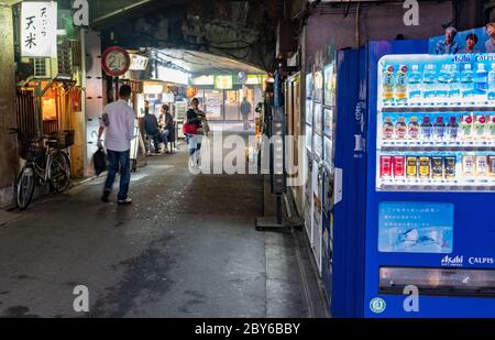 Leute, die in der Hintergasse des Yurakucho-Bezirks, Tokio, Japan bei Nacht spazieren gehen. Stockfoto