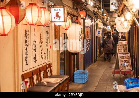 Leute, die in der Hintergasse des Yurakucho-Bezirks, Tokio, Japan bei Nacht spazieren gehen. Stockfoto