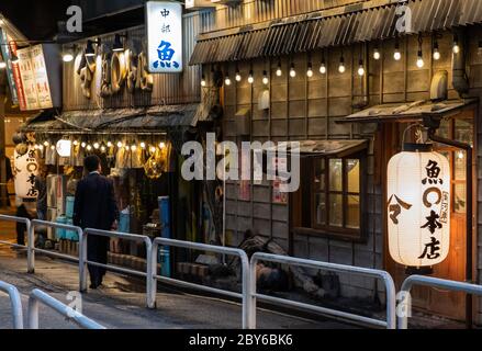 Leute, die in der Hintergasse des Yurakucho-Bezirks, Tokio, Japan bei Nacht spazieren gehen. Stockfoto