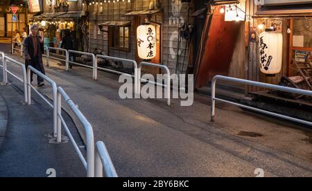 Leute, die in der Hintergasse des Yurakucho-Bezirks, Tokio, Japan bei Nacht spazieren gehen. Stockfoto