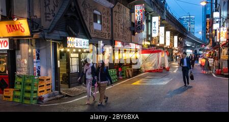 Leute, die in der Hintergasse des Yurakucho-Bezirks, Tokio, Japan bei Nacht spazieren gehen. Stockfoto