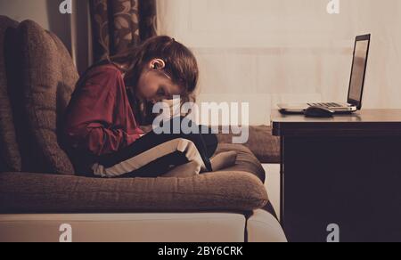Unglücklich niedlichen Kind Mädchen sitzt auf dem Sofa in der Nähe des Computers und spielen in mobilen Spielen zu Hause. Nahaufnahme Vintage getöntes Porträt. Stockfoto
