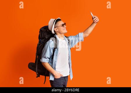 Aufgeregt Kerl Abenteurer unter Selfie beim Gehen über orangefarbenen Hintergrund Stockfoto