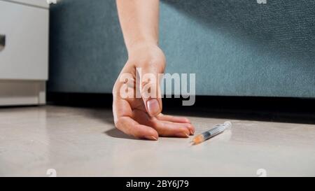 Frau einer toten Frau mit Drogenabhängigkeit, die mit Spritze auf dem Boden liegt Stockfoto