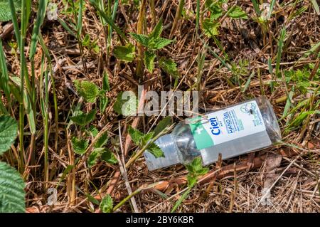 Der neue Müll - eine leere Flasche Handdesinfektionsmittel, die an einem Straßenrand weggeworfen wird. Stockfoto