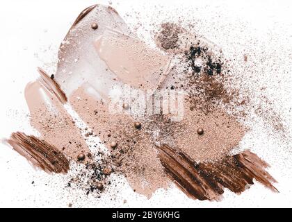 Beauty Konzept in beigen Farben. Verschmierte Make-up-Foundation, gebrochene Schatten, verschmierter Lippenstift und funkelt auf weißem Hintergrund. Stockfoto