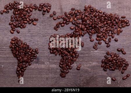 Dramatische Foto der Weltkarte aus arabisch gerösteten Kaffeebohnen auf alten Vintage-Holztisch. Stockfoto