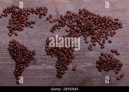 Dramatische Foto der Weltkarte aus arabisch gerösteten Kaffeebohnen auf alten Vintage-Holztisch. Stockfoto