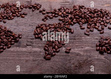 Dramatische Foto der Weltkarte aus arabisch gerösteten Kaffeebohnen auf alten Vintage-Holztisch. Stockfoto