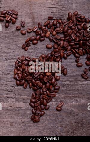 Dramatische Foto der Weltkarte aus arabisch gerösteten Kaffeebohnen auf alten Vintage-Holztisch. Stockfoto