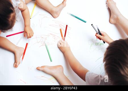 Talentierte Kinder zeichnen mit farbigen Filzstiften auf weißem Papier, Unterricht, Aufgaben mit Kindern des unterschiedlichen Alters Stockfoto