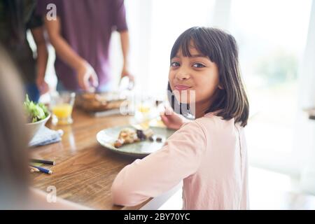 Portrait glücklich Mädchen essen Mittagessen mit Familie am Tisch Stockfoto