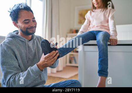 Vater hilft Tochter anziehen Schuhe Stockfoto