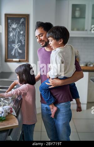 Vater und Kinder beim Geschirr in der Küche Stockfoto