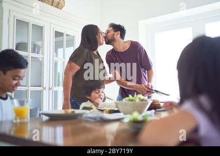 Liebevolles Paar küsst am Esstisch Stockfoto