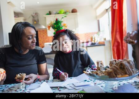 Portrait Mutter und Tochter beim Schreiben von Weihnachtskarten am Tisch Stockfoto