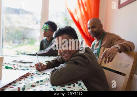 Portrait glücklich Junge schreiben Weihnachtskarten am Tisch Stockfoto