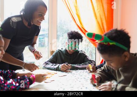 Glückliche Mutter und Töchter dekorieren Weihnachtskekse am Tisch Stockfoto