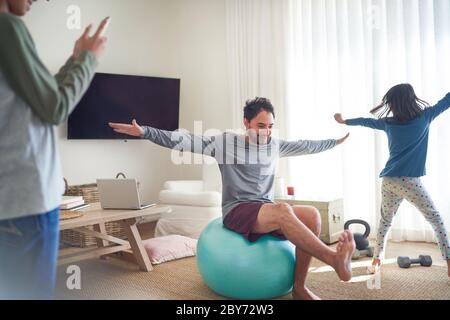 Vater und Kinder trainieren und spielen im Wohnzimmer Stockfoto