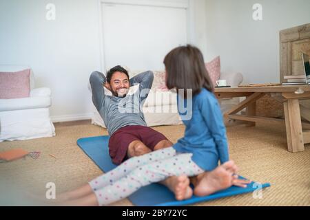 Spielerisch Vater und Tochter trainieren im Wohnzimmer Stockfoto