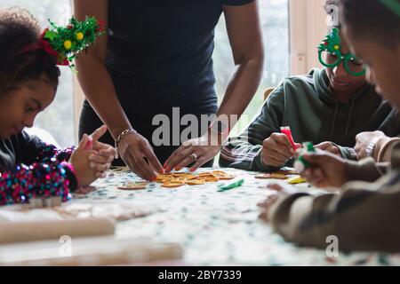 Familie dekorieren Weihnachtskekse am Tisch Stockfoto