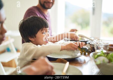 Happy Boy spielt mit Spielzeug Dinosaurier am Esstisch Stockfoto