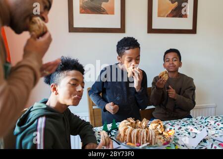 Vater und Söhne essen Weihnachtskuchen am Tisch Stockfoto