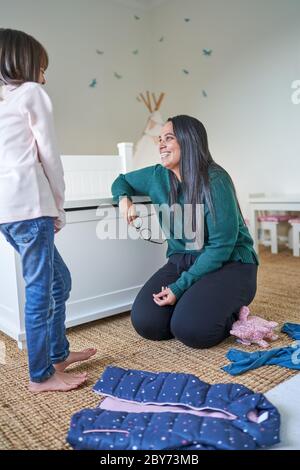 Glückliche Mutter und Tochter machen Wäsche im Schlafzimmer Stockfoto