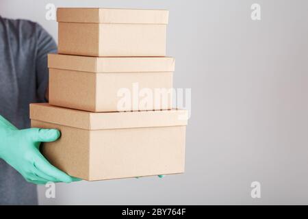 Der Kurier hält ein Paket von Kartons mit blauen Gummihandschuhen in der Hand. Stockfoto
