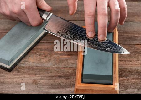 Mann schärft ein Kochmesser mit Damaststahl Stockfoto