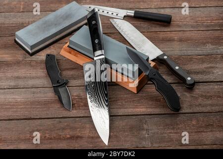 Verschiedene Messer und Schärfsteine auf einem rustikalen Holztisch Stockfoto