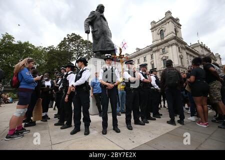 Polizei bildet sich um die Sir Winston Churchill Statue auf dem Parliament Square, London, vor einer Kundgebung an der Nelson Mandela Statue auf dem Platz, um George Floyd zu gedenken, Als seine Beerdigung findet in den USA nach seinem Tod am 25. Mai, während in Polizeigewahrsam in der US-Stadt Minneapolis. Stockfoto