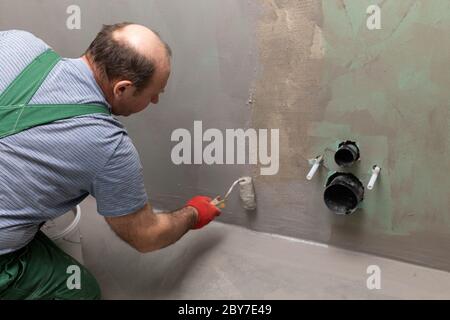 Badezimmer renoviert. Bauarbeiter. Isolierung mit mineralischer Feuchtigkeit. Während der Arbeit. Stockfoto