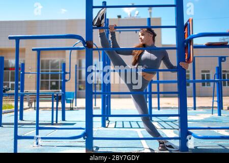 Junge schlanke Frau tun Garn um Beine zu strecken. Positive Mädchen, die Splits. Stockfoto