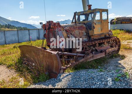 Ein alter verrostete Traktor steht in den Bergen, um ihn herum sprießt Gras. Stockfoto