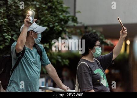 Hongkong, China. Juni 2020. Ein Mann und eine Frau schließen sich Hunderten von Hongkongern an, indem sie ihre Mobiltelefone aus Protest zum einjährigen Jahrestag des Starts der prodemokratischen Proteste in Hongkong anheben. Quelle: Ben Marans/Alamy Live News. Stockfoto