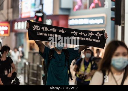 Hongkong, China. Juni 2020. Ein Mann hält ein Protestschild neben Hunderten von Hongkongern, die sich einem Polizeiverbot widersetzen und die Straßen im zentralen Geschäftsviertel übernehmen, um den einjährigen Jahrestag der prodemokratischen Proteste in Hongkong zu begehen.Quelle: Ben Marans/Alamy Live News. Stockfoto