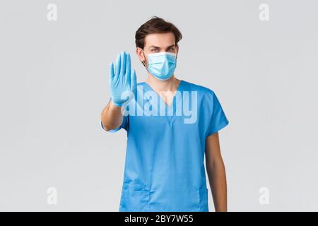 Coronavirus Ausbruch, Gesundheitsarbeiter Bekämpfung von Krankheiten, Krankenhäuser Konzept. Selbstbewusster Arzt in medizinischen Maske, blaue Peelings und Handschuhe, zeigt Stop Stockfoto