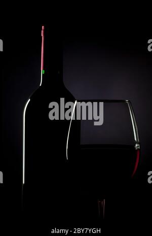 Flasche und Glas Rotwein bei schwachem Licht Stockfoto