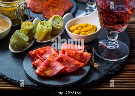 Auswahl an Tapas und Antipasti auf schwarzem Hintergrund. Charcuterie-Boards mit verschiedenen Vorspeisen. Stockfoto