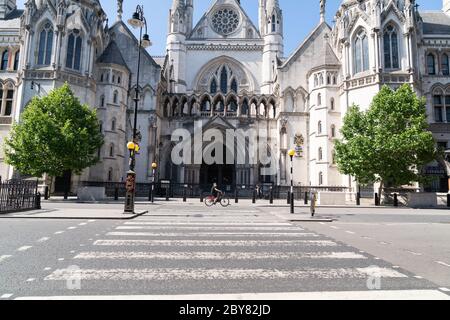 Geschlossen Royal Courts of Justice in London wegen Coronavirus COVID-19 mit einem Radfahrer vor dem Tragen einer Gesichtsmaske Stockfoto