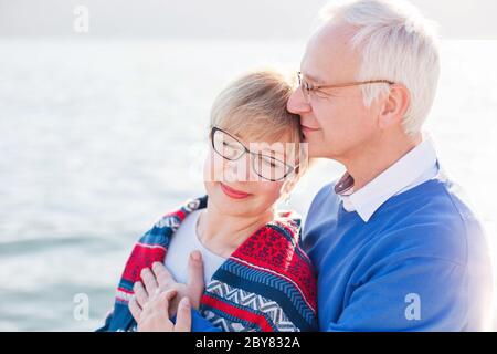 Ältere Paare genießen Ruhestand und Leben am Strand im Freien. Glücklicher Mann und Frau umarmen, umarmen