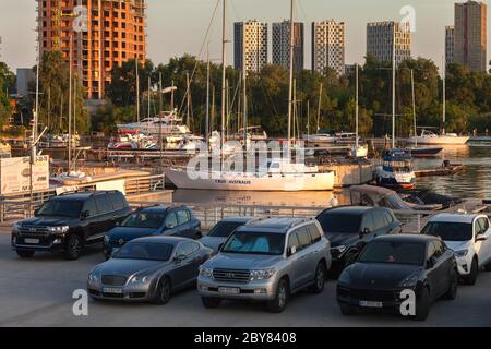 Kiew, Ukraine - 8. Juni 2020: Der Fluss Parkplatz von Segelyachten und privaten Motorbooten auf einem Fluss Pier in Kiew, und im Vordergrund sind die Autos ihrer Besitzer. Stockfoto